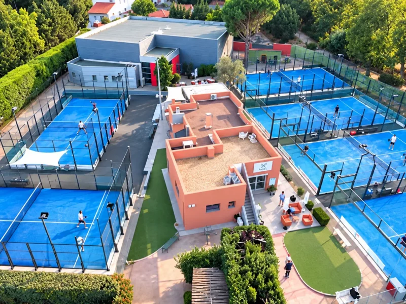 Club de padel vu du ciel : terrains bleus, joueurs et club-house