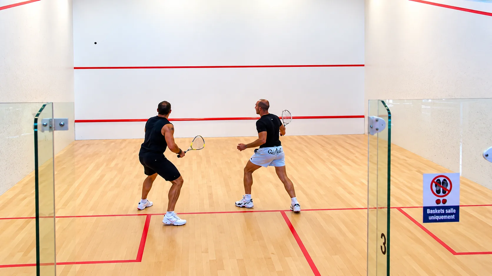 Deux joueurs en plein échange sur un court de squash
