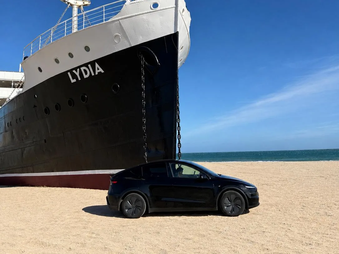 Tesla Model Y noire sur la plage du Barcarès, devant la proue du paquebot Lydia